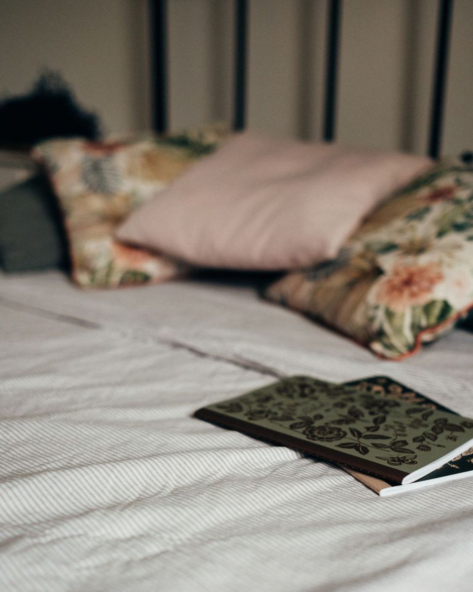 Una cama con cojines y un cuaderno abierto